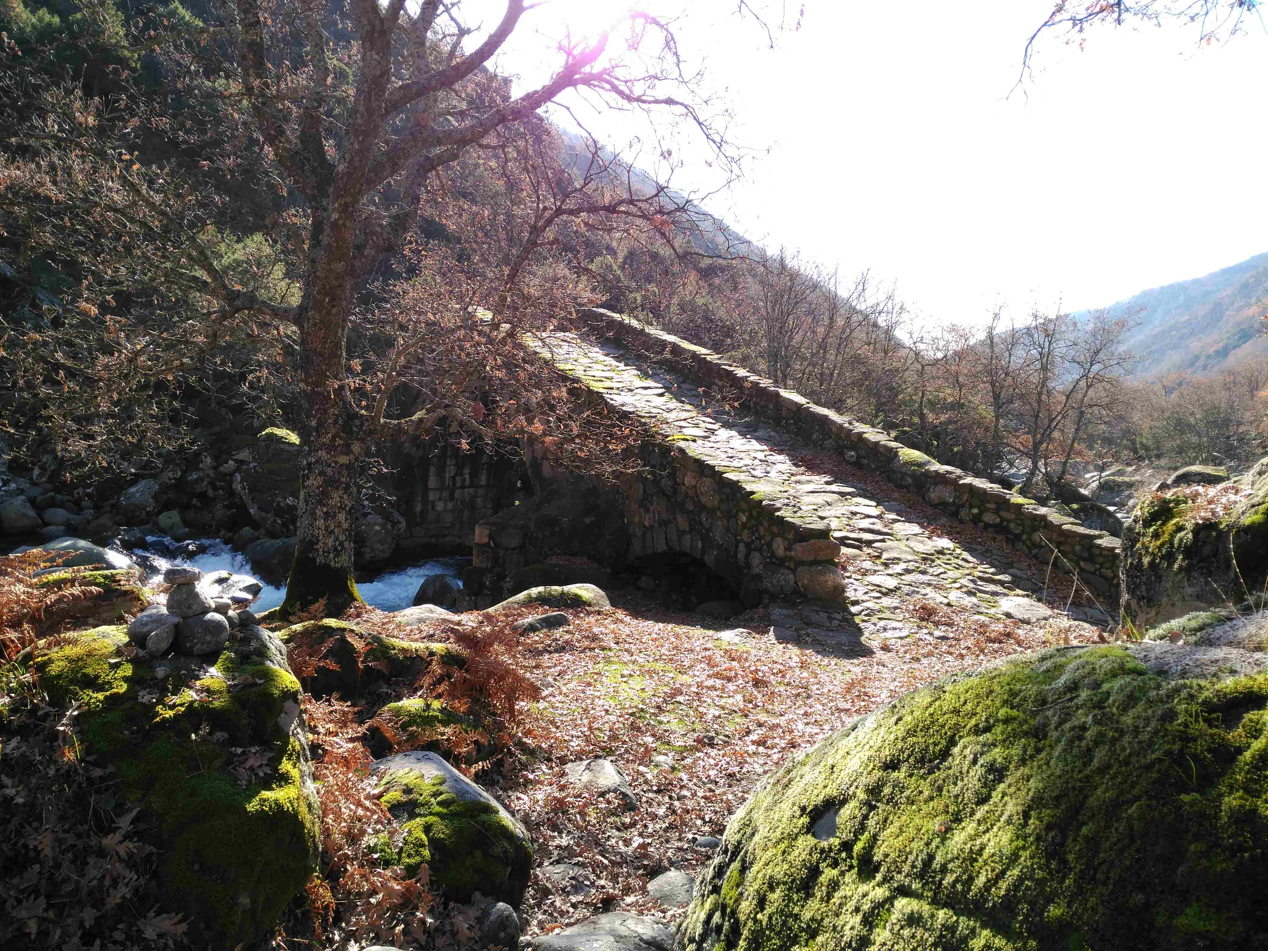 Puente de piedra entre montañas en otoño